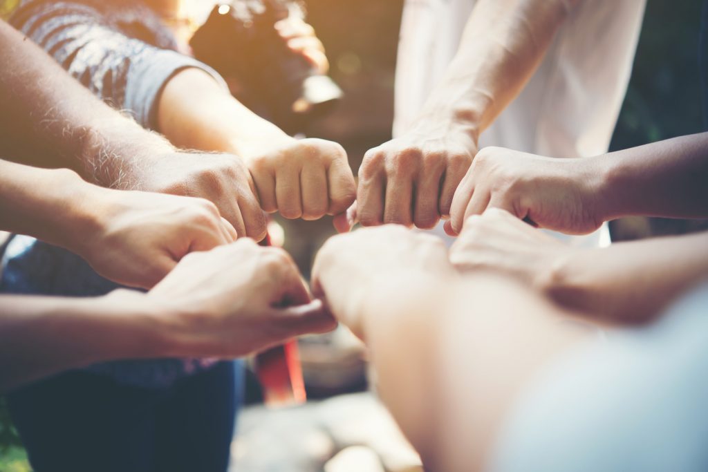 Individuals placing their fists together
