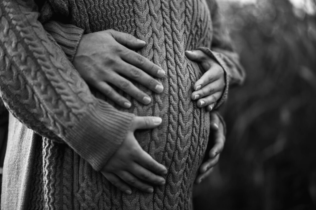 unrecognizable man embracing tummy of pregnant beloved on street