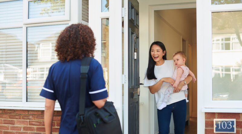 Mom and baby welcome home visitor at front door